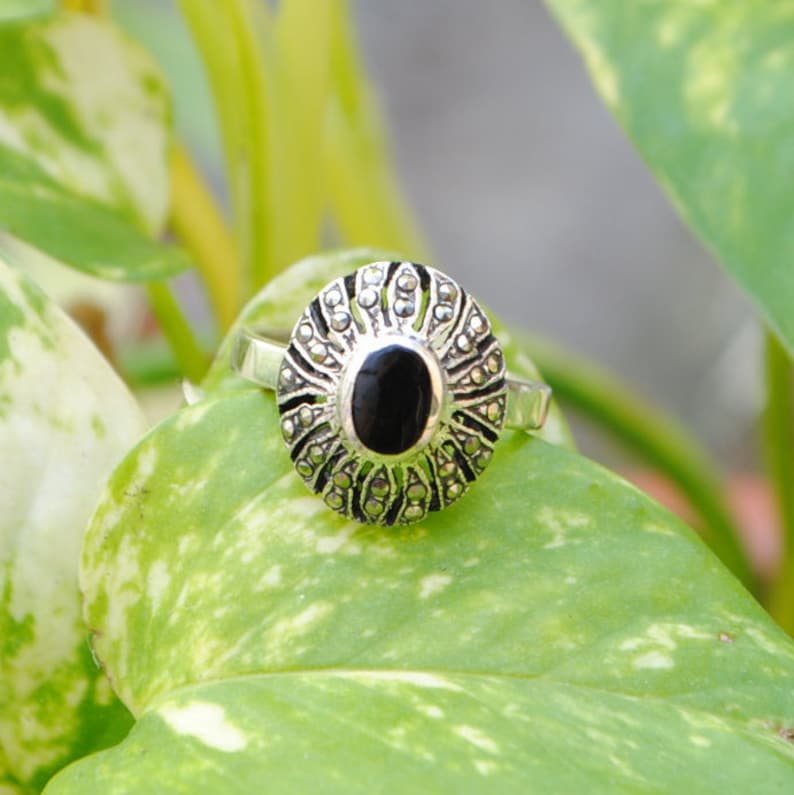Peut inclure: Une bague en argent avec une pierre d'onyx noire entourée de pierres de marcassite.