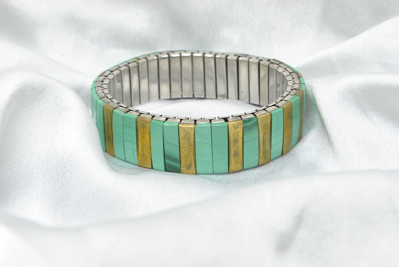 May include: A green and gold stretchy bracelet with a metal band.
