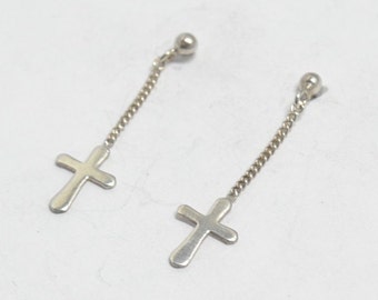 May include: A pair of silver dangle earrings with a cross charm hanging from a chain. The earrings have a small ball at the top.