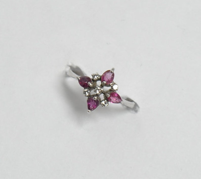 May include: A silver ring with a flower-shaped design featuring pink gemstones and small white diamonds.