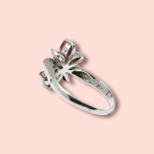 Op de afbeelding: Een zilveren ring met een roze bloemmotief. De ring is gemarkeerd met het nummer "925" aan de binnenkant van de band.