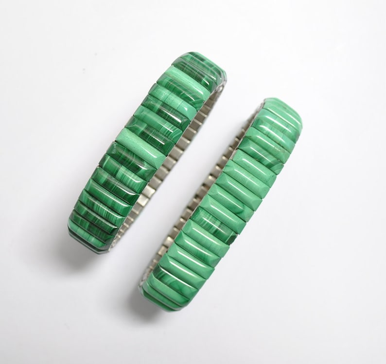 May include: Two green malachite stone bracelets with a silver metal band.
