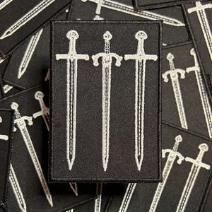 May include: Black embroidered patch with three white swords, a popular symbol of strength and power.