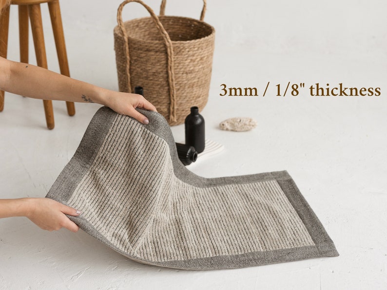 May include: A gray and white bath mat with a textured surface and a gray border. The mat is 3mm / 1/8" thick.