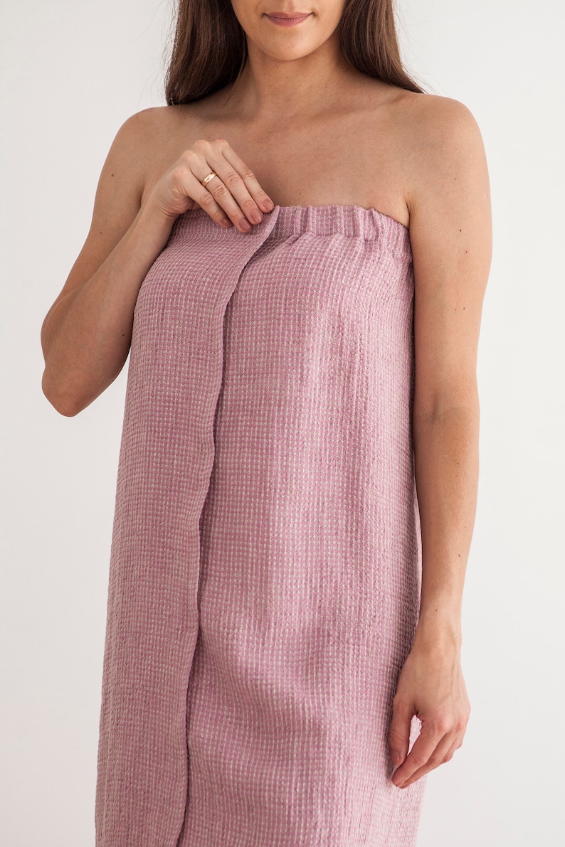 Pu&ograve; includere: Un accappatoio rosa in tessuto a nido d'ape con uno stile avvolgente e una chiusura a bottone singolo.