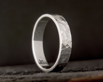 May include: A silver hammered wedding band. The band is smooth on the inside and has a hammered texture on the outside.