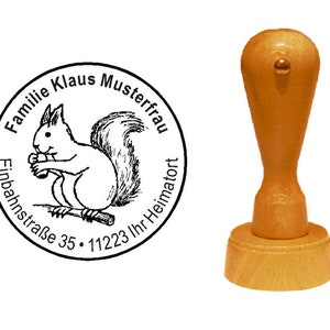 Peut inclure: Un tampon encreur en bois avec un motif rond représentant un écureuil de dessin animé tenant une noix. Le texte autour de l'écureuil est "Familie Klaus Musterfrau Einbahnstraße 35. 11223 Ihr Heimatort".