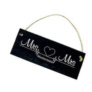 Puede incluir: Un letrero de pizarra negra con una cuerda blanca para colgar. El letrero dice "Mrs. Mustermann Mrs." con un corazón y una línea de latido del corazón.