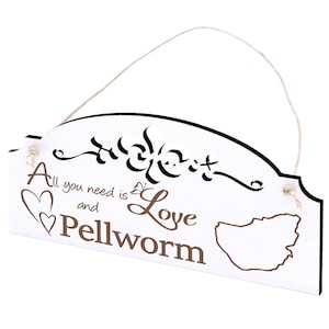 Könnte beinhalten: Ein weißes Holzschild mit schwarzem Rahmen und einem braunen Seil zum Aufhängen. Das Schild hat oben ein dekoratives Ausschnittmuster und den Text "All you need is Love and Pellworm" in braunen Buchstaben. Das Schild zeigt außerdem einen weißen Umriss der Insel Pellworm.