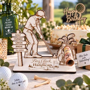 Könnte beinhalten: Ein hölzerner Golf-Aufsteller mit einer Golfer-Figur, einem Wegweiser mit Golfbegriffen und einer Golftasche. Auf der Basis steht der Text 'Fürs Glück gibt's kein Handicap.' Ein gerollter 50-Euro-Schein steckt in der Golftasche.