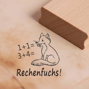 Könnte beinhalten: Ein Holzstempel mit einer Schwarzweißillustration eines Fuchses mit dem Text "1+1= 3+4= Rechenfuchs!"