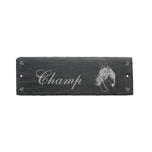 Könnte beinhalten: Schwarzes Schiefer-Pferdeboxenschild mit dem Namen "Champ" in weißer Schrift und einer Pferdekopf-Silhouette.
