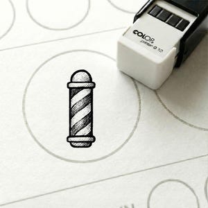 Könnte beinhalten: Ein schwarz-weißer Stempelabdruck einer Barbierstange in einem grauen Kreis. Der Stempel befindet sich auf weißem Papier, mit einem weißen und schwarzen Stempel in der oberen rechten Ecke. Der Stempel lautet "COLOR printer Q 12".