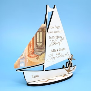 Op de afbeelding: Een houten zeilboot met een wit zeil en een geldbiljetzeil. De boot heeft een anker en de naam "Lina" aan de zijkant. Het zeil heeft tekst in het Duits. De boot staat op een blauwe achtergrond.