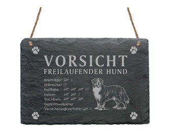 Könnte beinhalten: Schwarzes Schiefer-Schild mit weißem Text, der "Vorsicht Freilaufender Hund" (Vorsicht freilaufender Hund) lautet. Das Schild zeigt ein Hundebild und eine Liste von Personen oder Dingen, vor denen der Hund möglicherweise vorsichtig ist, darunter Briefträger, Einbrecher und Zusteller.