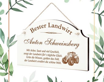 Op de afbeelding: Een wit houten bord met bruine tekst die "Bester Landwirt Anton Schweinsberg" luidt. Het bord heeft een bruine tractorafbeelding en een citaat over het belang van boeren.