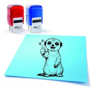 Könnte beinhalten: Zwei selbstfärbende Stempel, einer rot und einer blau, neben einem hellblauen Papier mit einer schwarzen Illustration eines Erdmännchens, das den Daumen hochhält. Die Stempel tragen den Text "COLOR primer Q 17".