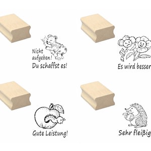 Può includere: Quattro timbri in legno con illustrazioni in bianco e nero e testo. I timbri mostrano un orso che scala un albero con il testo "Nicht aufgeben! Du schaffst es!" (Non arrenderti! Ce la farai!), un fiore con un viso triste e un fiore con un viso felice con il testo "Es wird besser!" (Andrà meglio!), una mela con un verme dentro con il testo "Gute Leistung!" (Buona prestazione!), e un riccio che tiene una mela con il testo "Sehr fleißig!" (Molto diligente!).