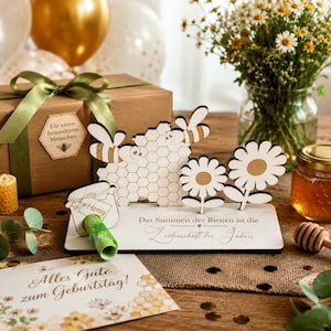 May include: A wooden decorative display featuring a honeycomb pattern, two bees, and two flowers on a rectangular base. The base includes the German text 'Das Summen der Bienen ist die Leidenschaft des Imkers' and a small jar cutout labelled 'Honig'.