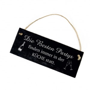 Peut inclure: Panneau rectangulaire en ardoise noire avec texte et illustrations blanches. Le panneau indique "Die Besten Partys finden immer in der KÜCHE statt." Une boucle en ficelle est attachée pour l'accrocher. Avec une bouteille de champagne et deux flûtes.