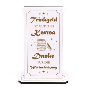May include: White wooden sign with the text "Trinkgeld ist gut fürs Karma Danke für die Wertschätzung" in brown lettering. The sign has a stack of gold coins and stars around the text.
