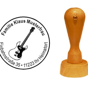 Può includere: Un timbro autoinchiostrante in legno con un design rotondo che presenta un'illustrazione in bianco e nero di una chitarra elettrica. Il testo intorno alla chitarra recita "Familie Klaus Musterfrau Einbahnstraße 35 - 11223 Ihr Heimatort".