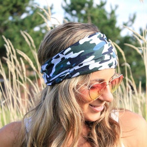 May include: A woman wearing a white and green camouflage headband with a blue and white pattern. She is wearing heart-shaped sunglasses and has long blonde hair.