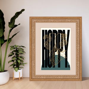 May include: A framed print with the word "HOPPY" in black letters with a gold leaf design. The background is a teal blue and white.
