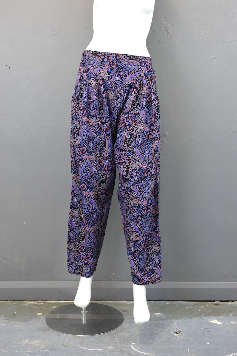 May include: Purple, black, and pink paisley print pants. The pants have a wide leg and a high waist.