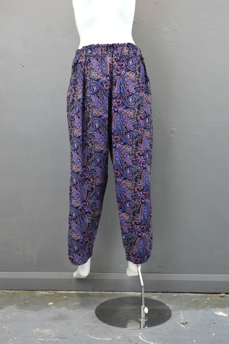 May include: Purple and pink paisley print pants with an elastic waistband.