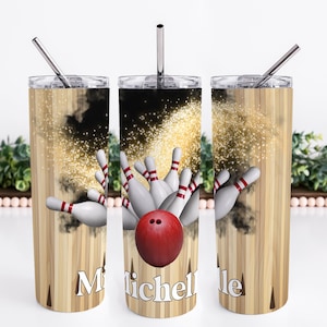 May include: A stainless steel tumbler with a bowling-themed design. The tumbler features a red bowling ball and white bowling pins against a wood grain background with gold glitter. The tumbler has a straw and the name "Michelle" is printed on the side.