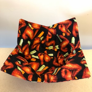 May include: A black fabric bowl with a pattern of red chicken wings and green celery stalks. The bowl is folded and ready to be used.