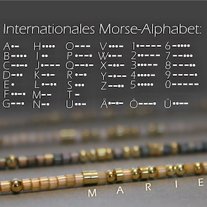 Peut inclure: Un bracelet en perles rapproché avec des perles dorées et blanches qui épellent le mot "MARIE". Le bracelet est sur une surface brune. L'alphabet du code Morse international est affiché en arrière-plan.
