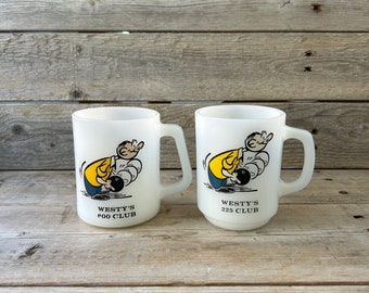 May include: Two white ceramic mugs with a cartoon bowler holding a bowling ball. The mugs have the text "Westy's 225 Club" and "Westy's 200 Club" printed on them.