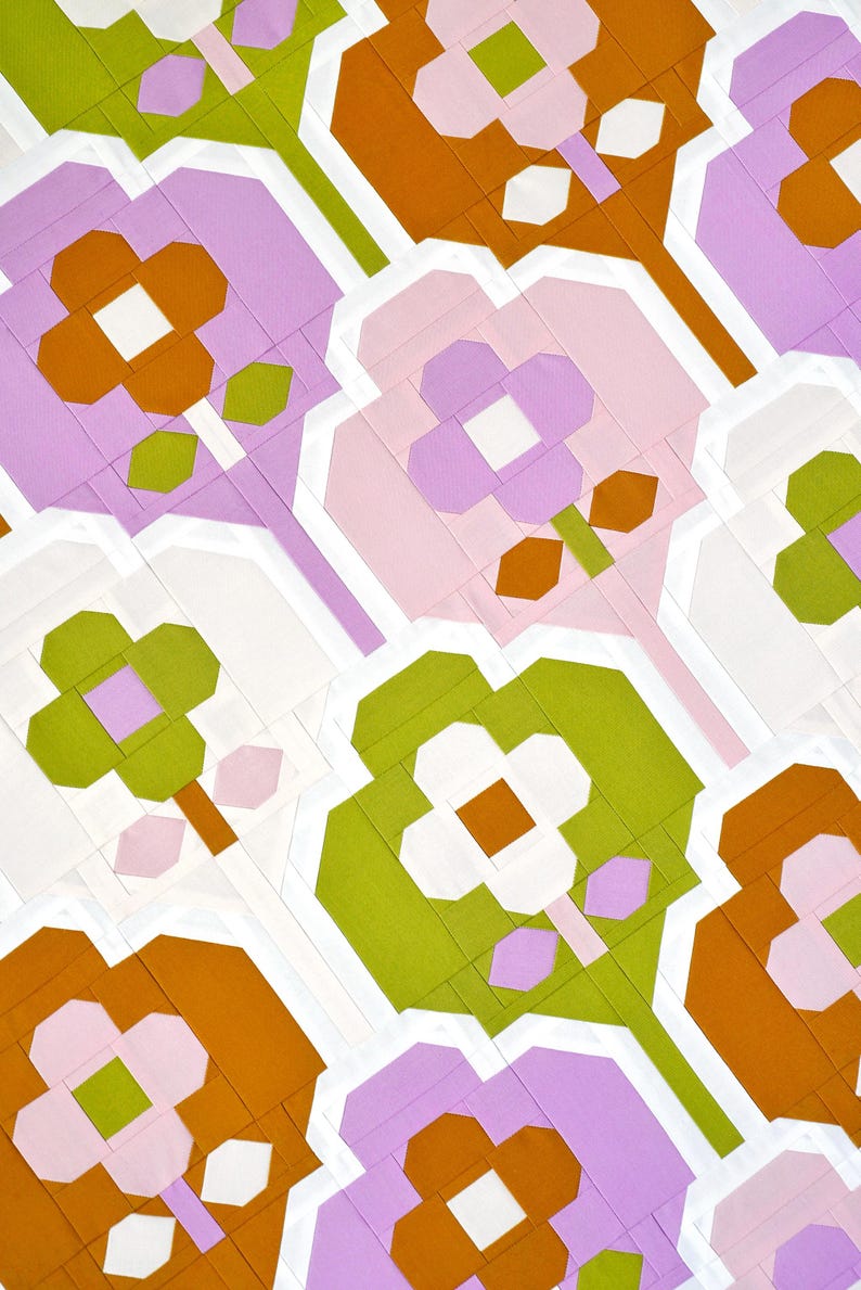 Op de afbeelding: Een herhalend patroon van abstracte bloemen in tinten roze, groen, wit en oranje. De bloemen zijn gemaakt van geometrische vormen en zijn in een verspringend patroon gerangschikt.