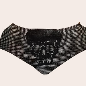 Puede incluir: Diseño de calavera negra sobre una tela de malla negra. La calavera está hecha a crochet y tiene un contorno blanco.