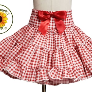 May include: Red and white gingham skirt with a red bow at the waist. The skirt has multiple layers of ruffles.