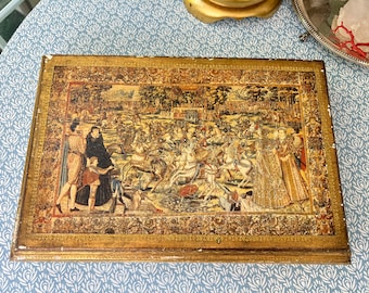 Könnte beinhalten: Eine Holzkiste mit goldfarbenem Rahmen und einem tapisserieartigen Bild einer mittelalterlichen Szene mit Rittern zu Pferd. Die Szene spielt in einem Wald mit einem Schloss im Hintergrund.