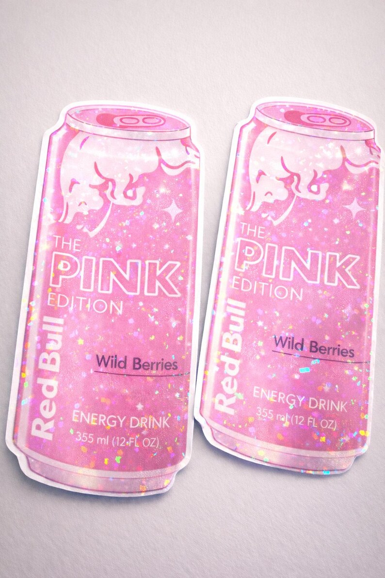 May include: Two pink Red Bull "The Pink Edition" stickers. The stickers feature a glittery design with the text "Wild Berries" and "Energy Drink 355 ml (12 FL OZ)". The Red Bull logo is visible on the can.