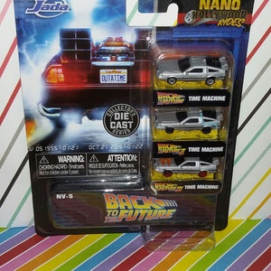 May include: A packaged set of Jada Nano Hollywood Rides die-cast model cars from the Back to the Future movie series. The package includes three miniature silver DeLorean time machines, with the license plate reading "OUTATIME".