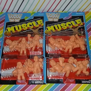 May include: A package of four sets of small, orange, plastic wrestling figures. Each set contains four figures. The packaging is red and white with the words "Millions of Unusual Small Creatures Lurking Everywhere!" and "MUSCLE" in black and white. The packaging also features the WWF logo.