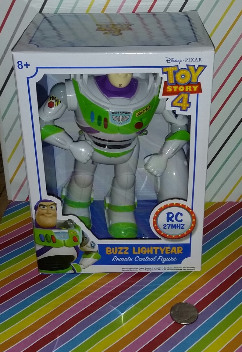 K&ouml;nnte beinhalten: Eine wei&szlig;e Box mit einer gr&uuml;n-wei&szlig;-violetten Buzz Lightyear Actionfigur. Auf der Box steht "Toy Story 4" und "RC 27MHZ". Die Figur h&auml;lt eine Laserpistole und tr&auml;gt einen gr&uuml;n-wei&szlig;en Space Ranger Anzug.
