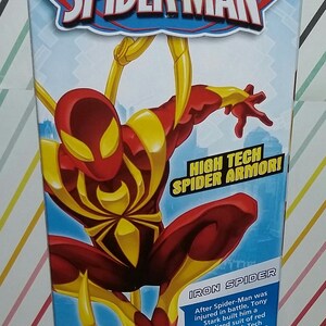 May include: A red and gold action figure of Iron Spider from the Ultimate Spider-Man series. The figure is posed in a dynamic action pose with its arms outstretched. The figure is wearing a high-tech suit with a spider symbol on the chest. The text on the box reads "High Tech Spider Armor!" and "Iron Spider".