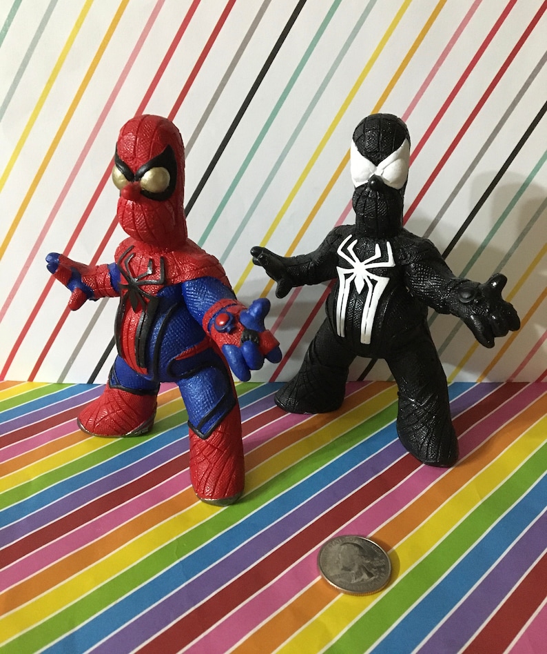 Peut inclure: Deux figurines faites &agrave; la main de Spider-Man, l'une en rouge et bleu et l'autre en noir. Le Spider-Man rouge et bleu a une grosse t&ecirc;te et une position large. Le Spider-Man noir a une t&ecirc;te plus petite et une position plus agressive.