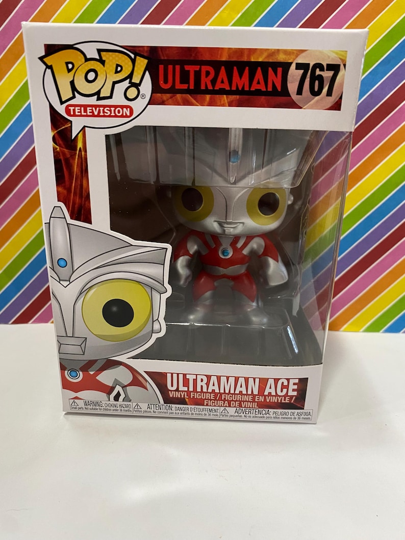以下が含まれることがあります： オリジナルパッケージに入った、Funko Pop!のウルトラマンエースのビニールフィギュア、ナンバー767。フィギュアは赤、銀、黄色です。箱にはPop! Televisionのロゴとウルトラマンエースの名前が記載されています。