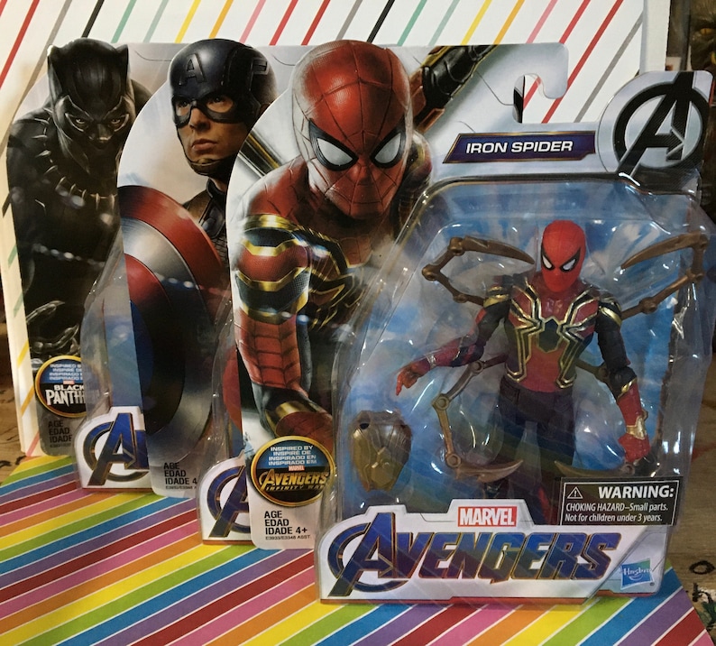 May include: Three action figure packaging boxes featuring Marvel Avengers characters. The boxes are red, blue, and black with images of Iron Spider, Captain America, and Black Panther. The Iron Spider box has the text "Iron Spider" and "Avengers" printed on it. The Captain America box has the text "Avengers" printed on it. The Black Panther box has the text "Black Panther" printed on it.