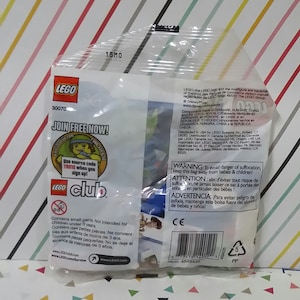 Puede incluir: Una bolsa de pl&aacute;stico que contiene un peque&ntilde;o set de juguetes LEGO con un fondo azul y rojo. La bolsa tiene una etiqueta de advertencia sobre las piezas peque&ntilde;as y no est&aacute; destinada a ni&ntilde;os menores de 3 a&ntilde;os. La bolsa tambi&eacute;n tiene un logotipo de LEGO club y una direcci&oacute;n de sitio web.