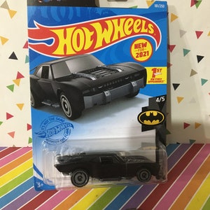 May include: A black Hot Wheels die-cast car of the Batman vehicle, packaged on a blue and black card. The card features the Hot Wheels logo, the Batman logo, and the text "NEW FOR 2021". The car is 4/5 in the series.