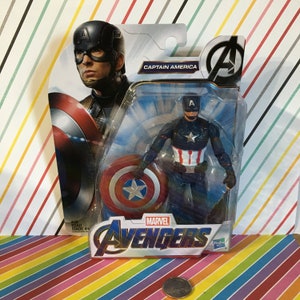 May include: A plastic action figure of Captain America from the Marvel Avengers movie series. The figure is holding a red, white, and blue shield and is wearing a blue and red costume with a star on the chest. The figure is packaged in a plastic blister pack with a blue and white background. The packaging features the Marvel Avengers logo and the words "Captain America".