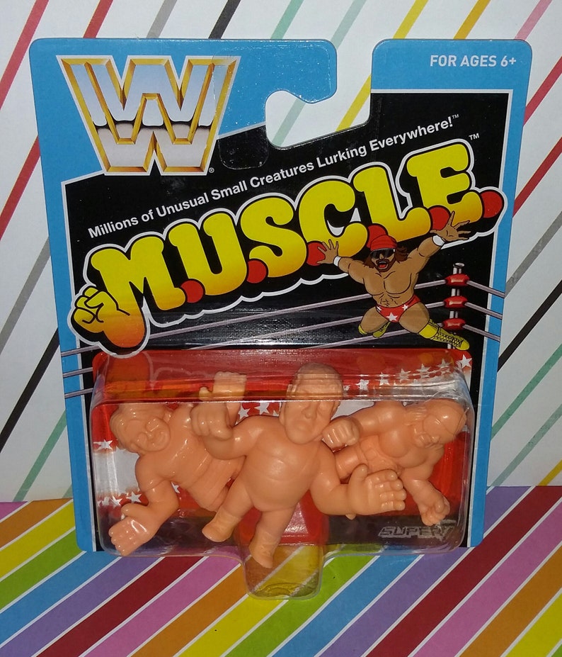May include: A package of three small, orange, plastic wrestling figures. The figures are in a clear plastic blister pack on a red and white background. The package has a blue header with the WWF logo and the words "Millions of Unusual Small Creatures Lurking Everywhere!" in white text. The package also has the words "MUSCLE" in yellow text on a black background. The package is labeled "FOR AGES 6+".